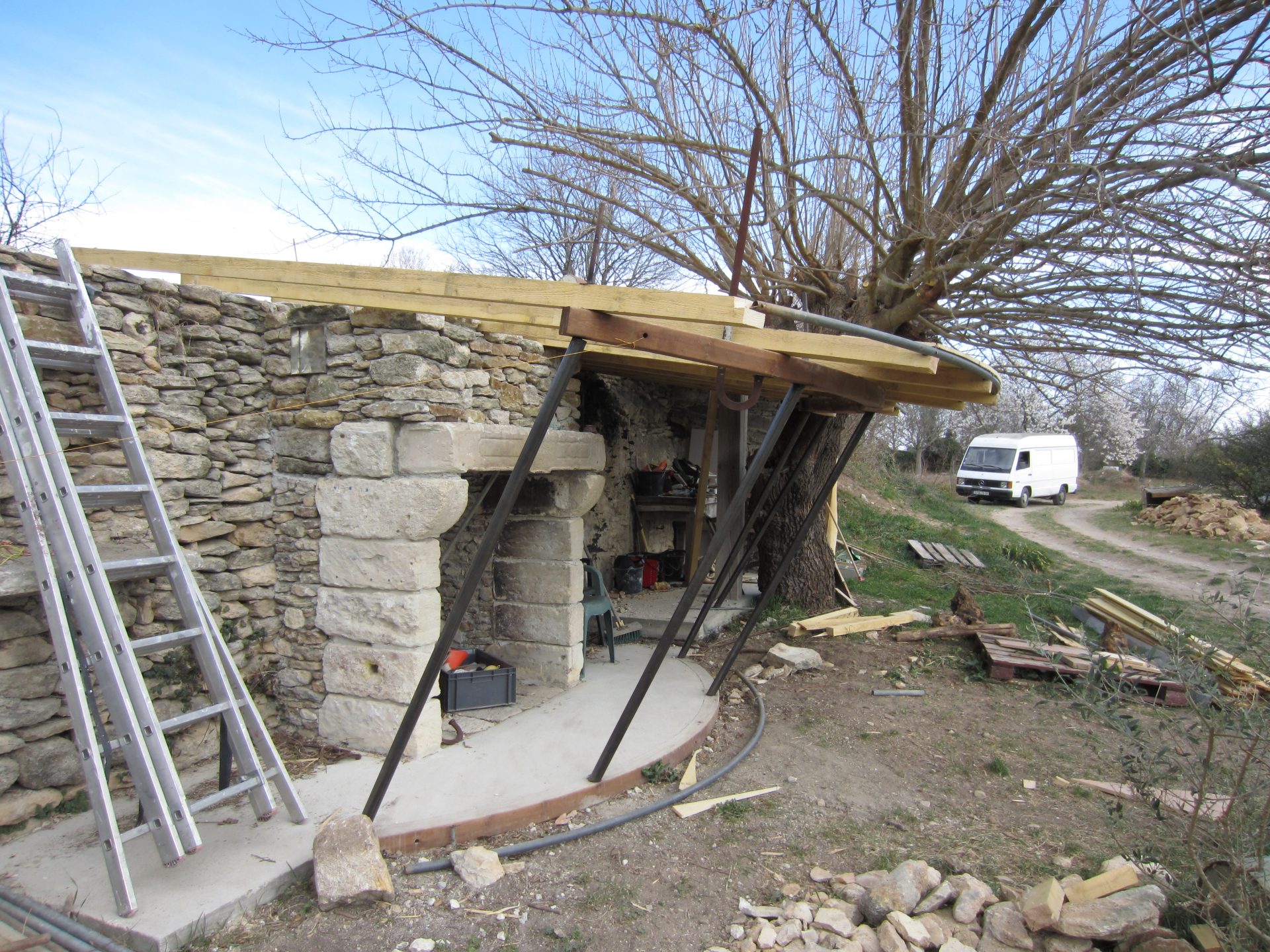 Abri extérieur : soubassement en pierre appareillée surmonté d'une toiture en bois de forme courbe.