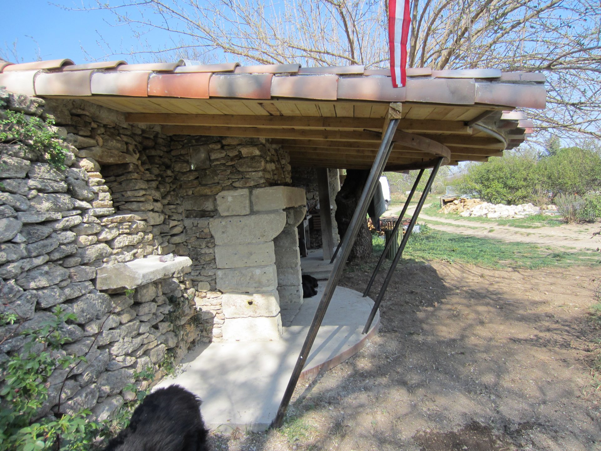 Détail des jambes d'acier inclinées qui portent la toiture bois de l'abri.
