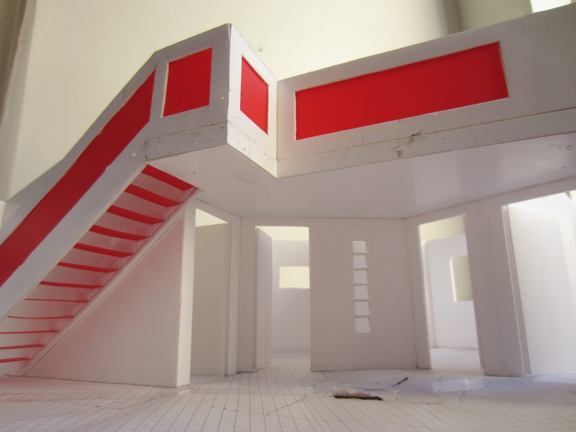 Vue intérieure de la maquette montrant l'escalier rouge et le bandeau qui court le long du mur.